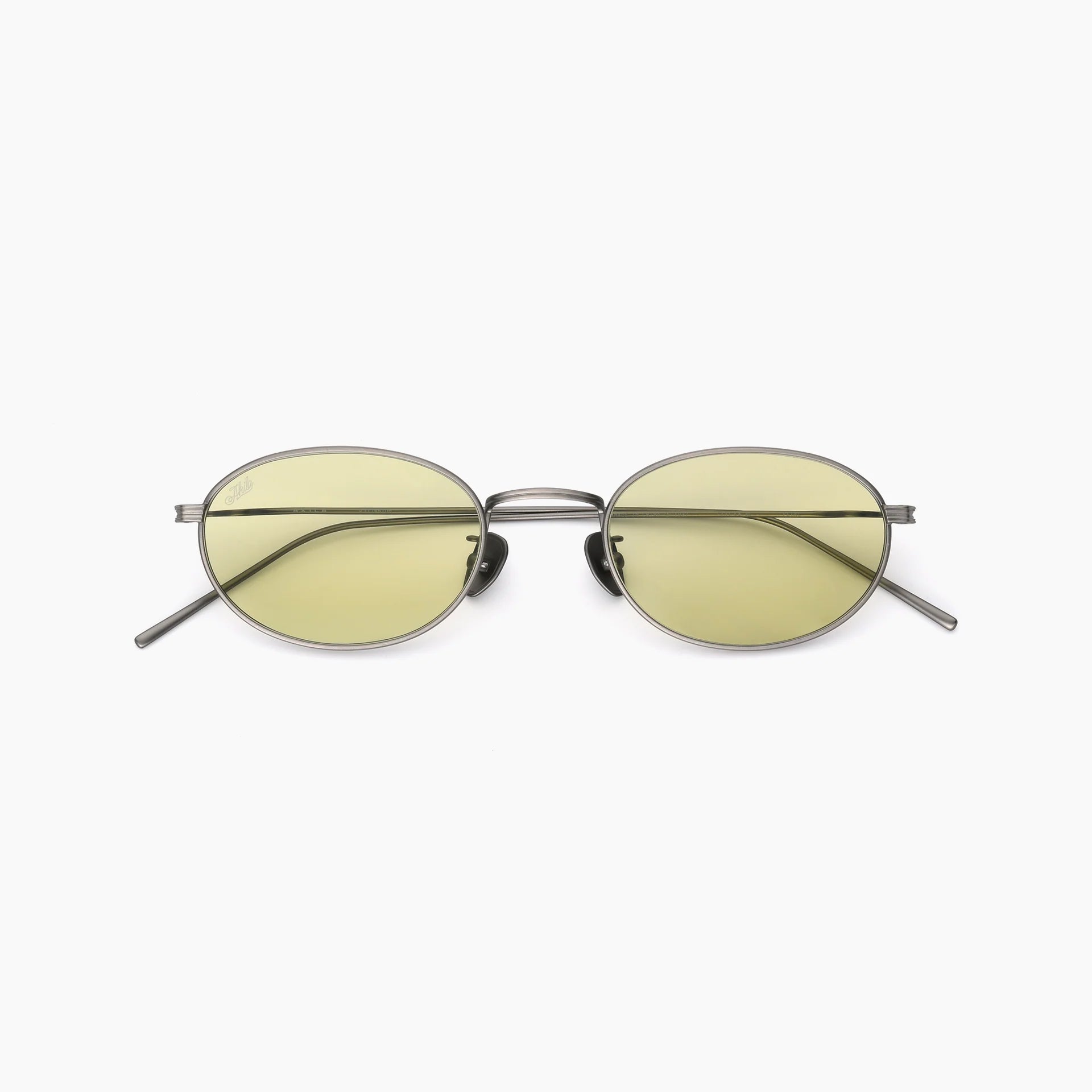 Oval metal-frame sunglasses with pale yellow lenses, adjustable nose pads, slim temples, and a double bridge, shown front-facing on a white background.