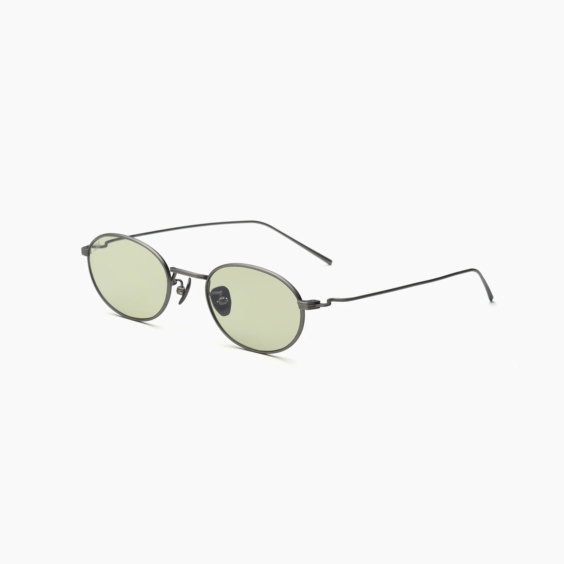 Oval metal-frame sunglasses with pale yellow lenses, adjustable nose pads, and slim wire temples, shown at an angled side view on a white background.