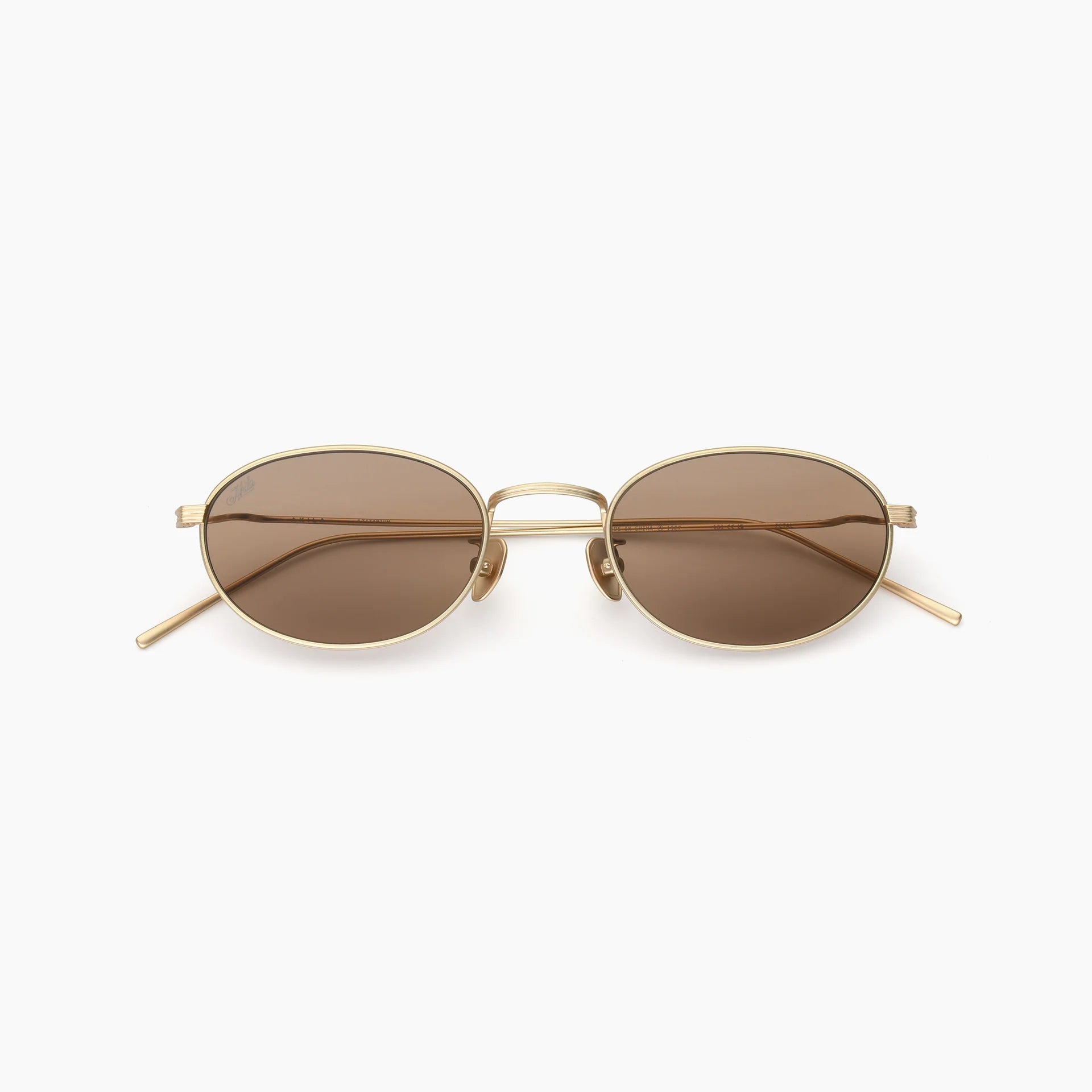 Oval gold metal-frame sunglasses with brown-tinted lenses, adjustable nose pads, slim temples, and a double bridge, shown front-facing on a white background.