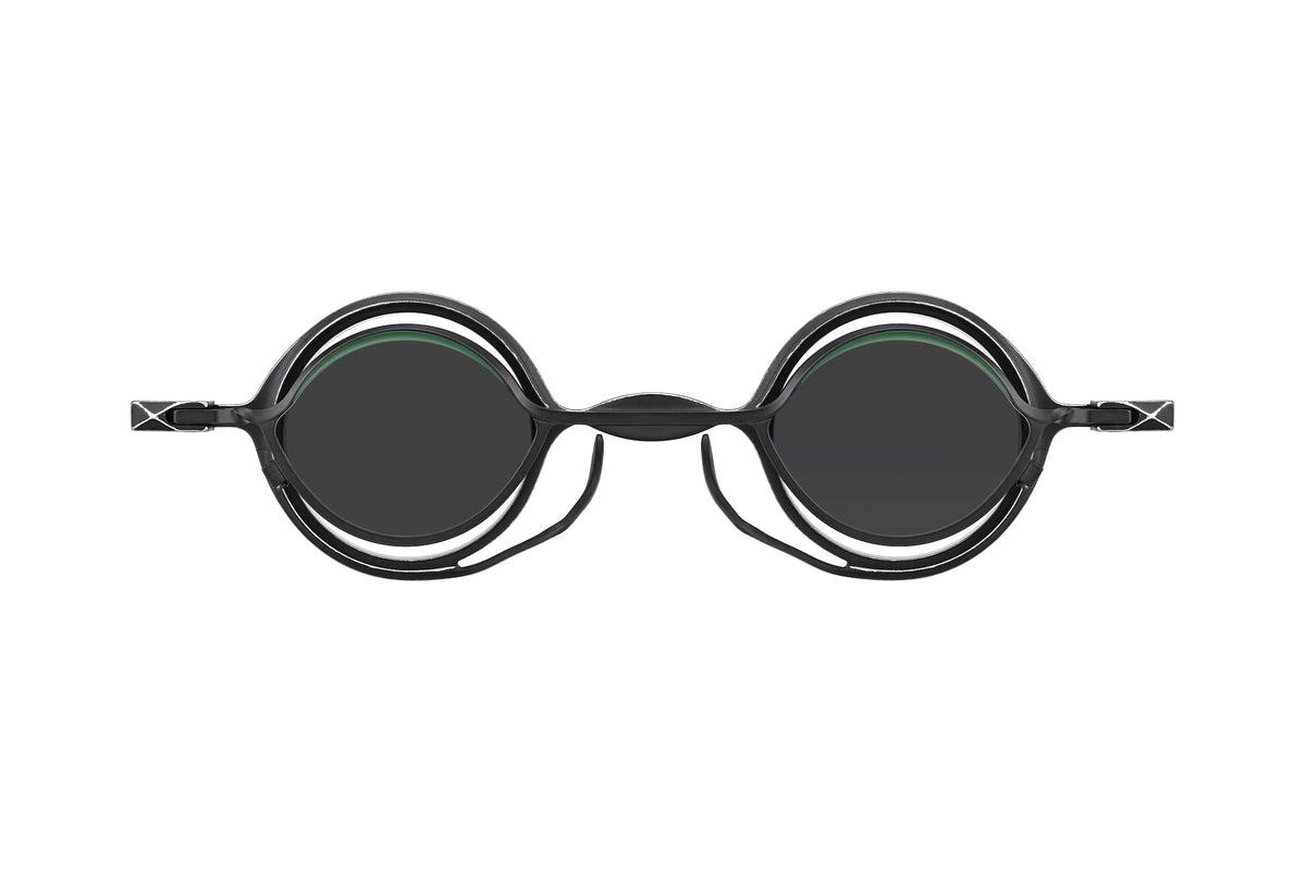 Front view of the RIGARDS RG0105TI by RIGARDS: bold, round black eyeglasses with thick frames and dark UV400 sun lenses on a white background. The modern design features open arms and offers superior eye protection.
