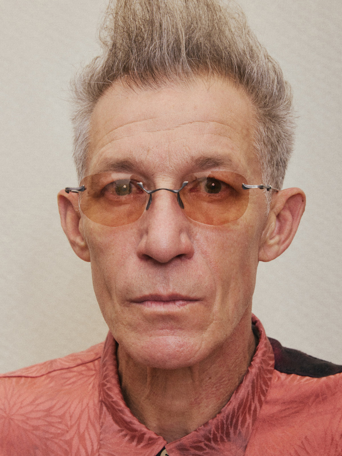 Model wearing rimless RIGARDS sunglasses with amber-tinted lenses and dark metal accents, photographed in a close-up portrait.