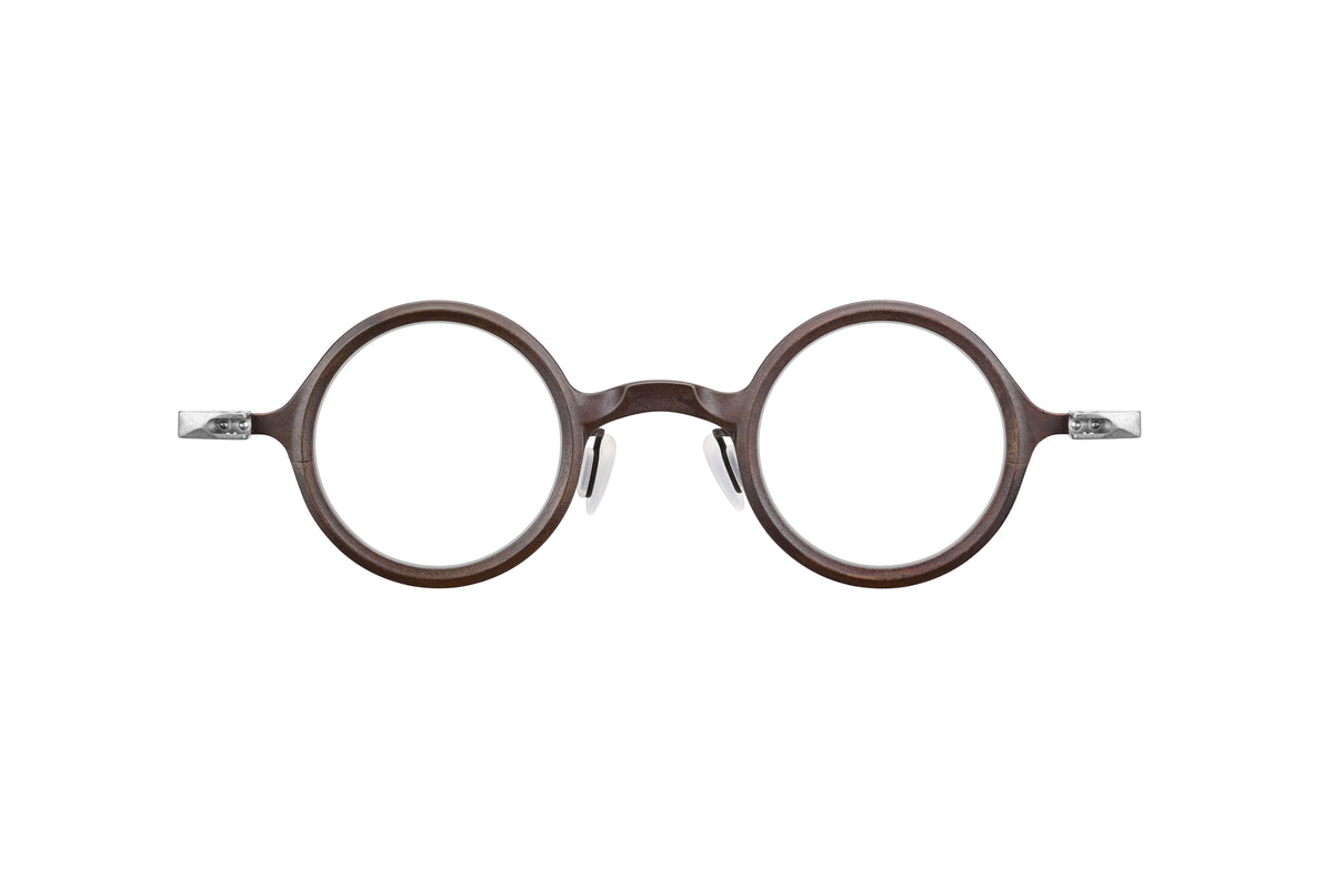 The RIGARDS RG1911TI eyeglasses by RIGARDS feature a round, brown frame with handcrafted titanium details and metal hinges, shown from the front on a white background.
