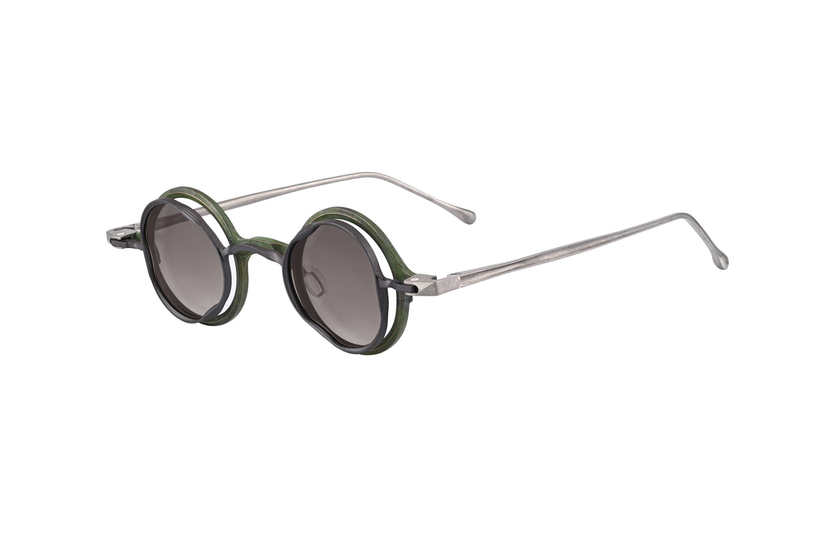 RIGARDS round sunglasses with dark grey lenses, layered black and green rims, and slim silver temples, shown from a three-quarter angle.