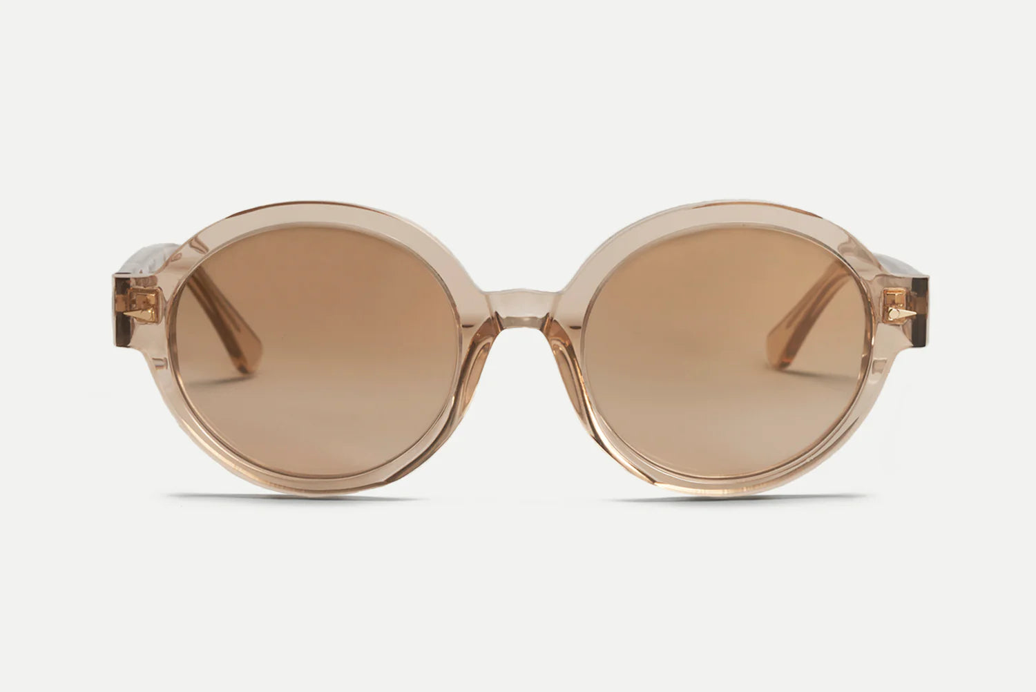 Oversized round sunglasses with translucent warm beige frames and matching brown-tinted lenses, shown against a light gray background.
