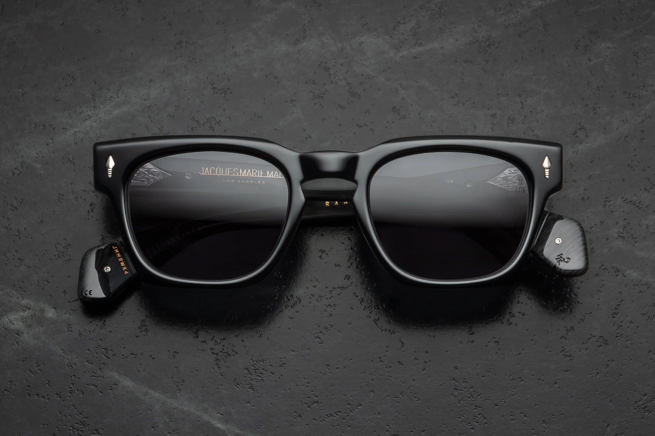 Black smart sunglasses with integrated electronic components on the temples, shown from a top-down view on a dark textured background.