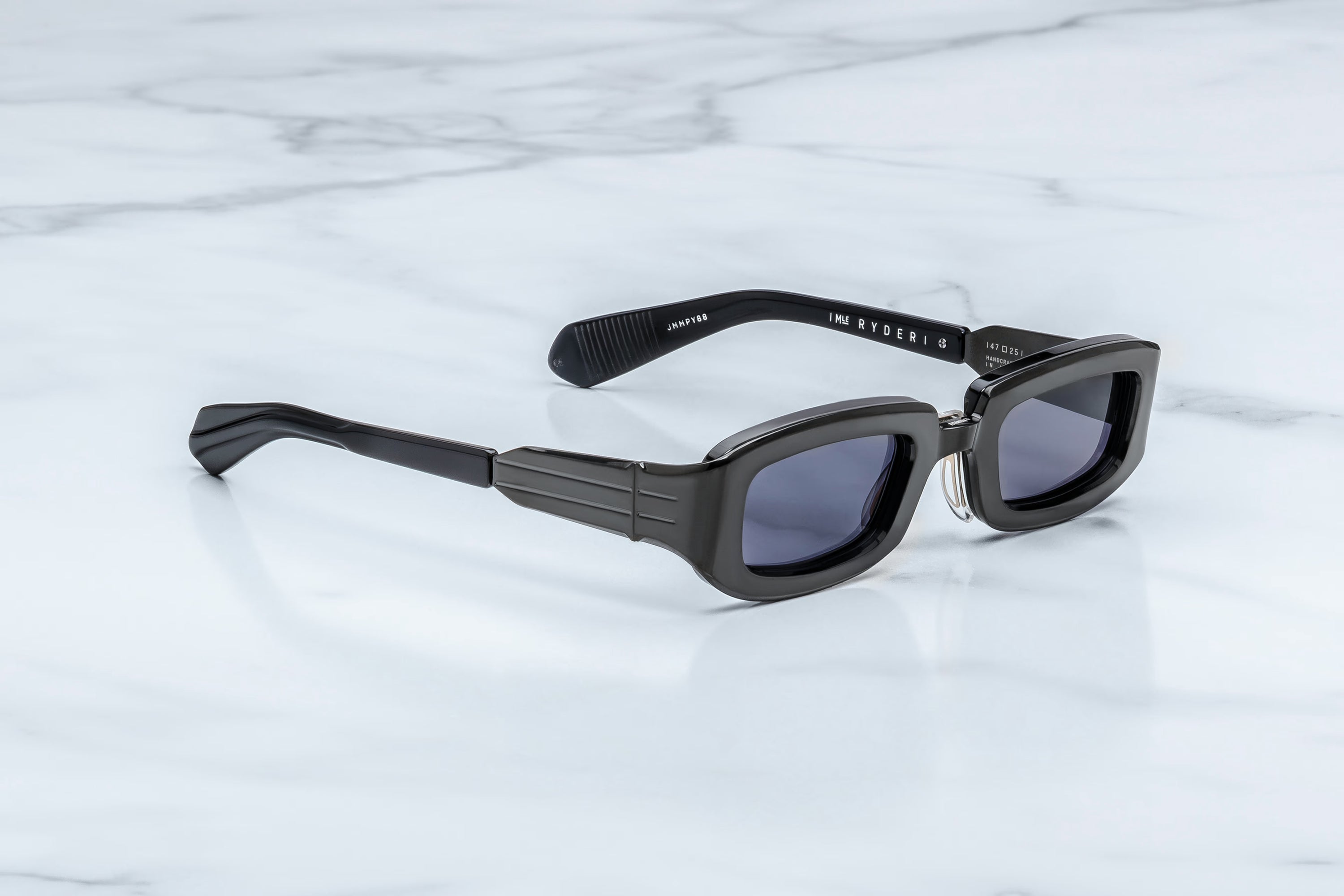 Black sunglasses with a brand logo on a light gray marble background
