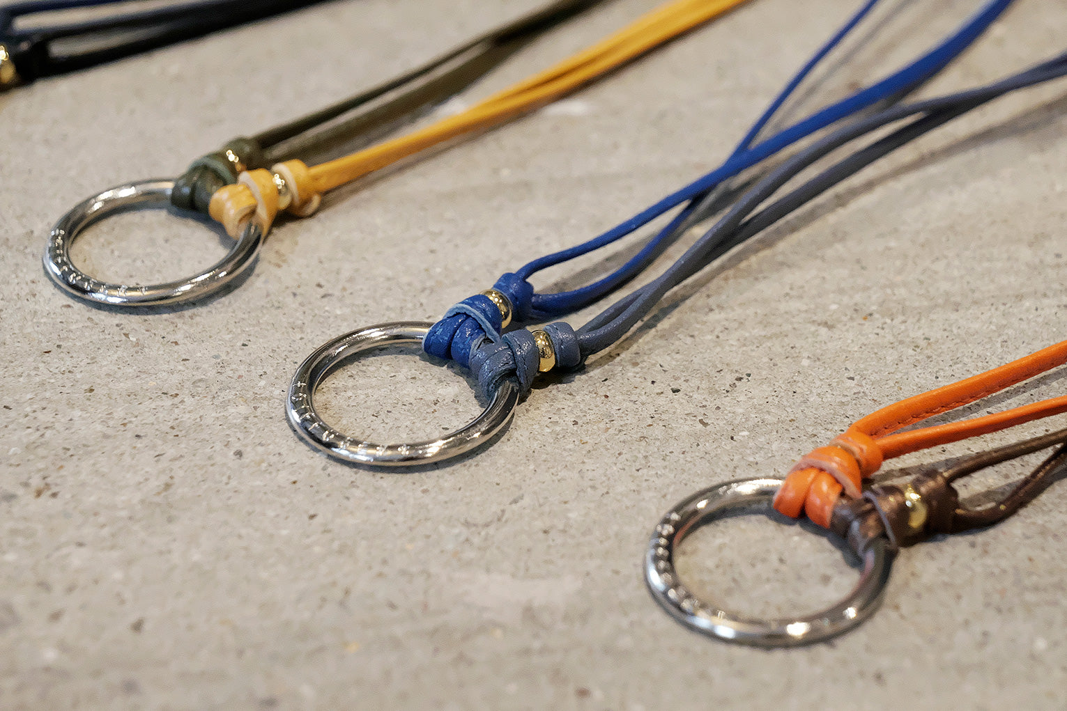 Close-up of three keychains with metal rings on a textured surface