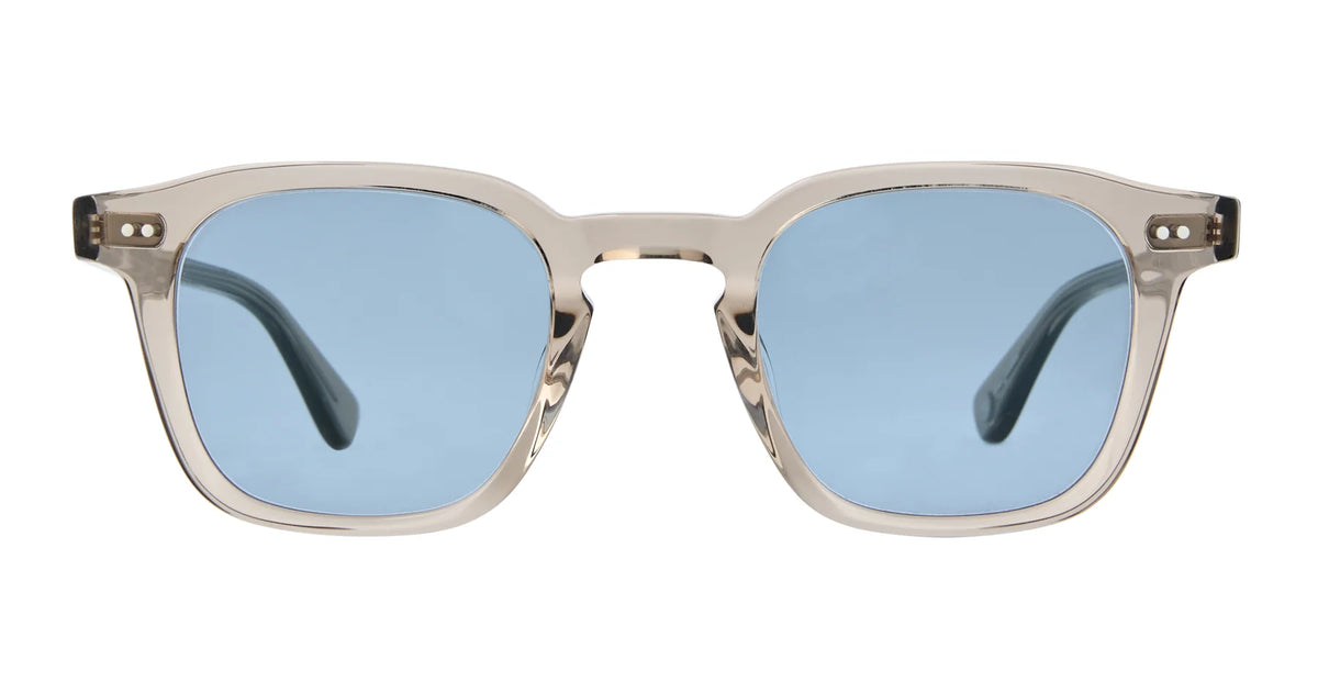 The Garrett Leight Verdugo by Garrett Leight are premium sunglasses featuring clear frames and rectangular blue-tinted lenses with UV protection, shown from the front against a white background.