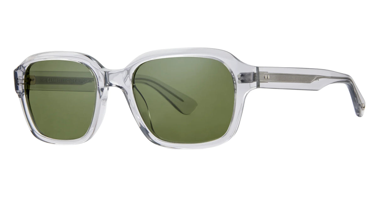 Garrett Leight Dominguez sunglasses by Garrett Leight, featuring clear vintage square frames and premium green-tinted glass lenses with UV protection, displayed at an angle on a white background.