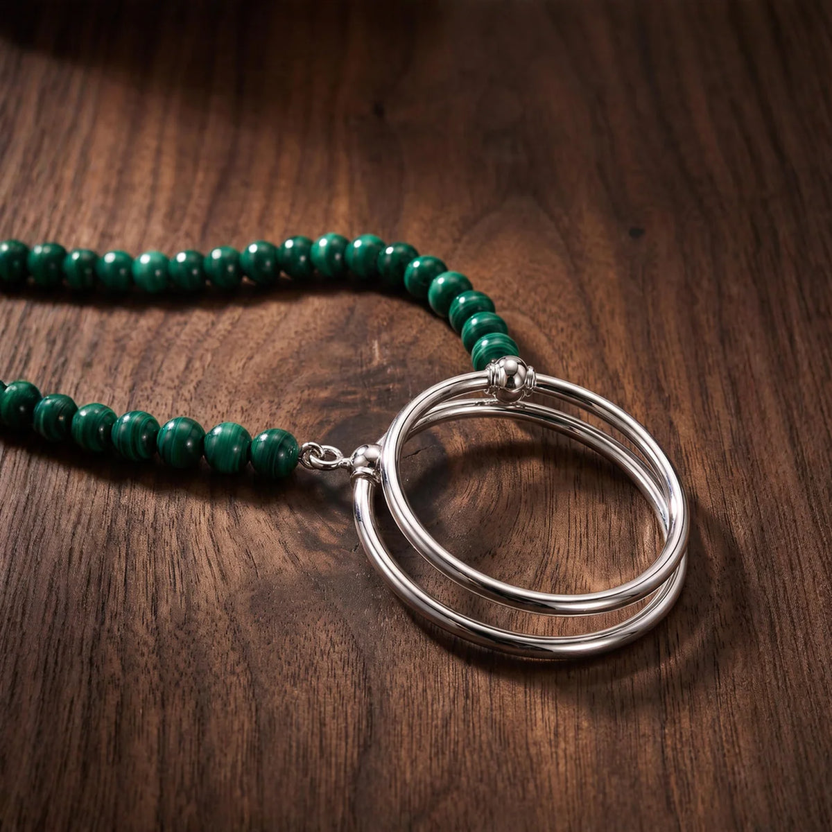 La Loop Luna handcrafted malachite bead necklace featuring a double silver-plated circular loop pendant.