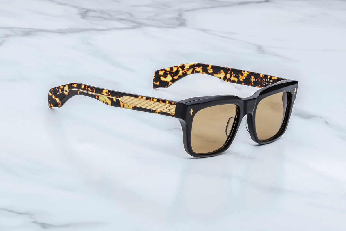 Jacques Marie Mage Torino ’60s-inspired black sunglasses with rectangular frames and tortoiseshell temples featuring gold accents and light brown lenses.