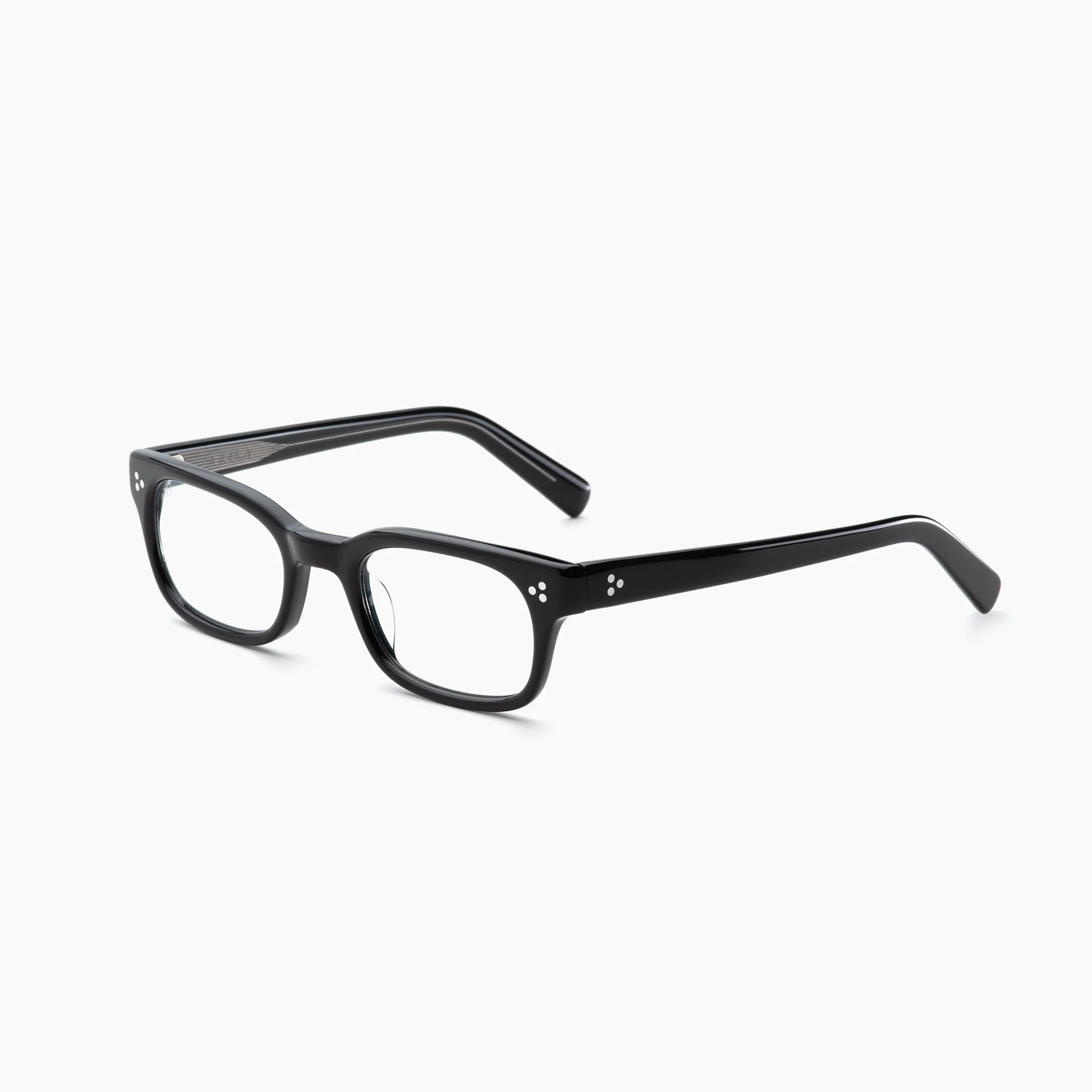 Akila Tracer black rectangular eyeglasses by Akila feature thick plastic frames with clear lenses, small silver dot accents near the hinges, and blue light blocking technology for enhanced eye protection, displayed on a white background.