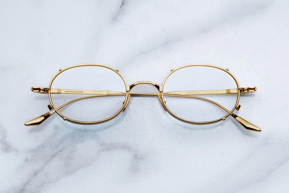 Jacques Marie Mage Violet minimalist oval glasses in a gold finish, featuring thin metal rims and temples.