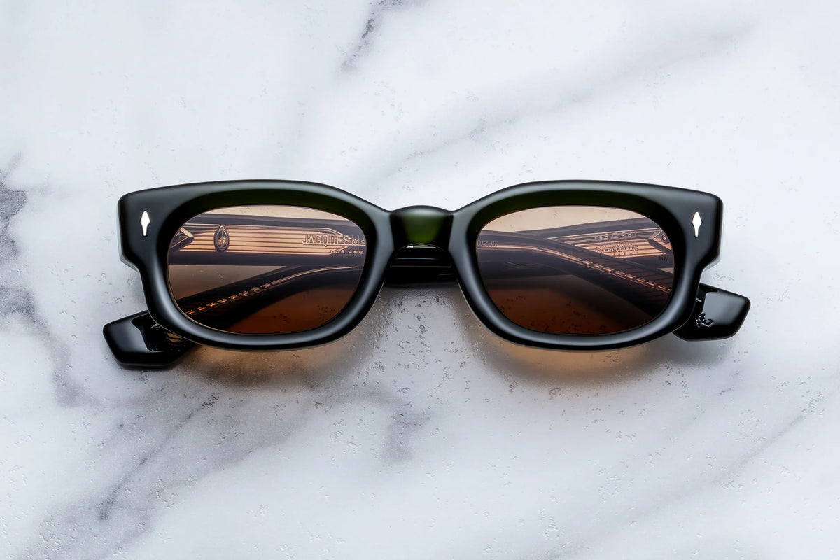 Jacques Marie Mage Whiskeyclone rectangular 90s-style sunglasses in dark green with brown tinted reflective lenses.
