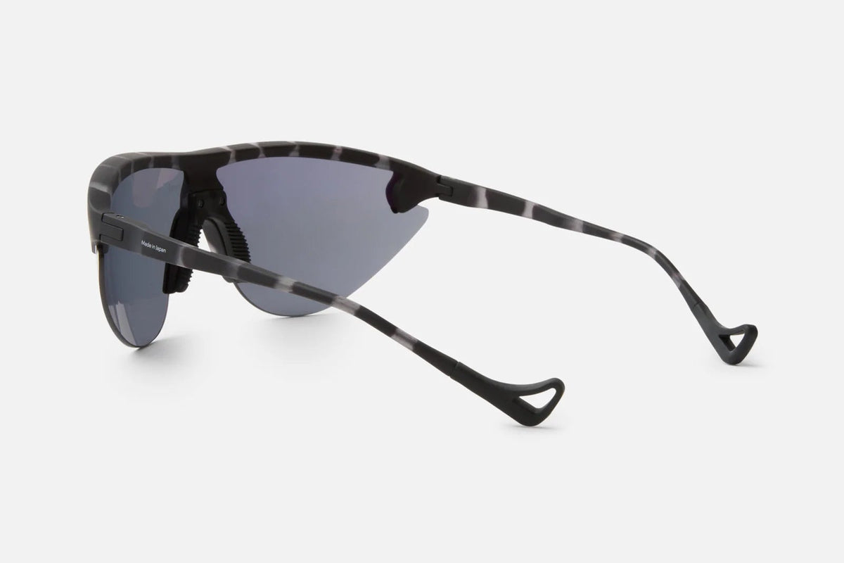 Side view of the District Vision Yukinori Range Finder sunglasses by District Vision, featuring sporty, wraparound dark angular lenses and black-and-gray patterned arms that curve at the tips. The sleek, lightweight frame is designed for an athletic and modern aesthetic.