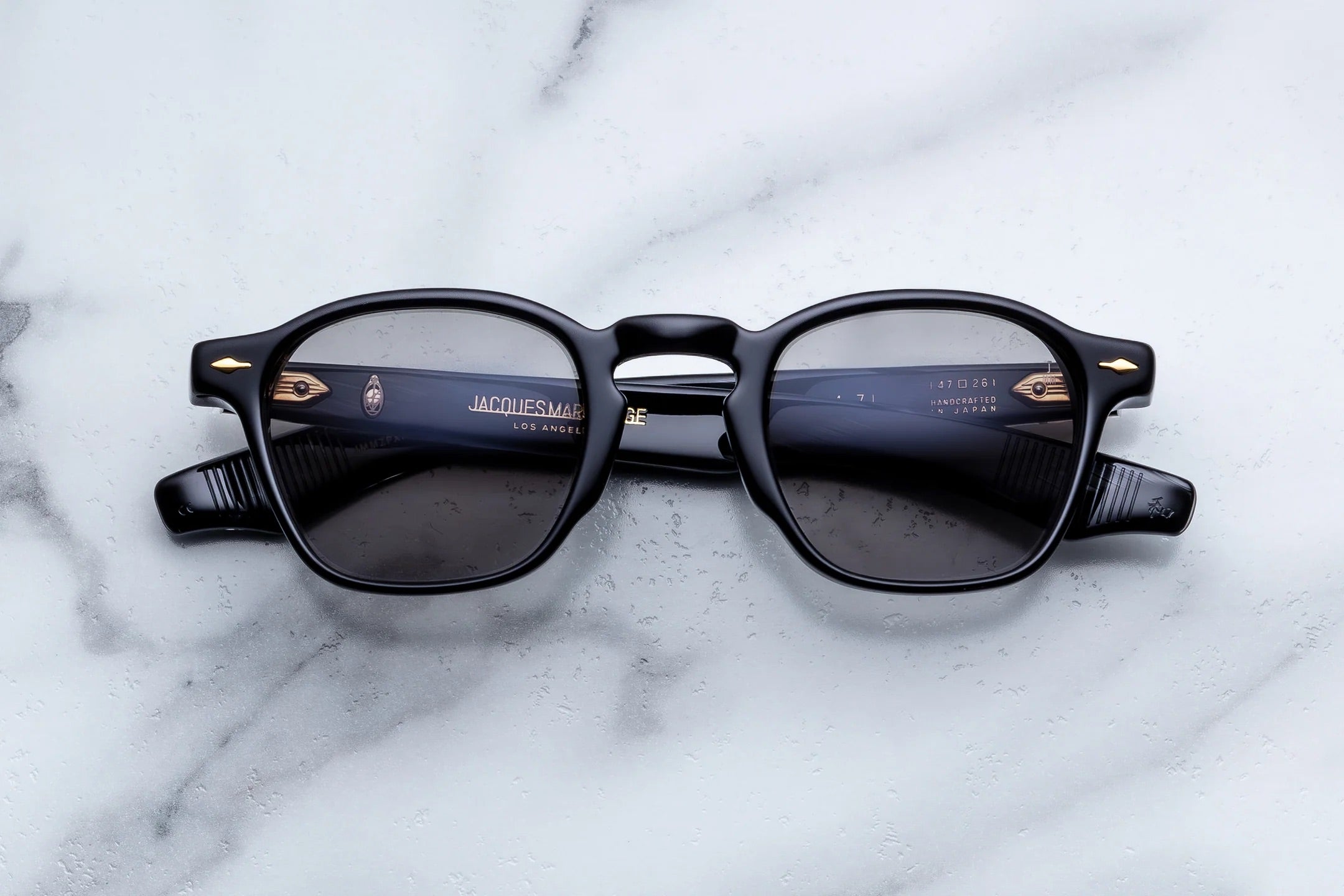 Black sunglasses with gold accents on a marble surface