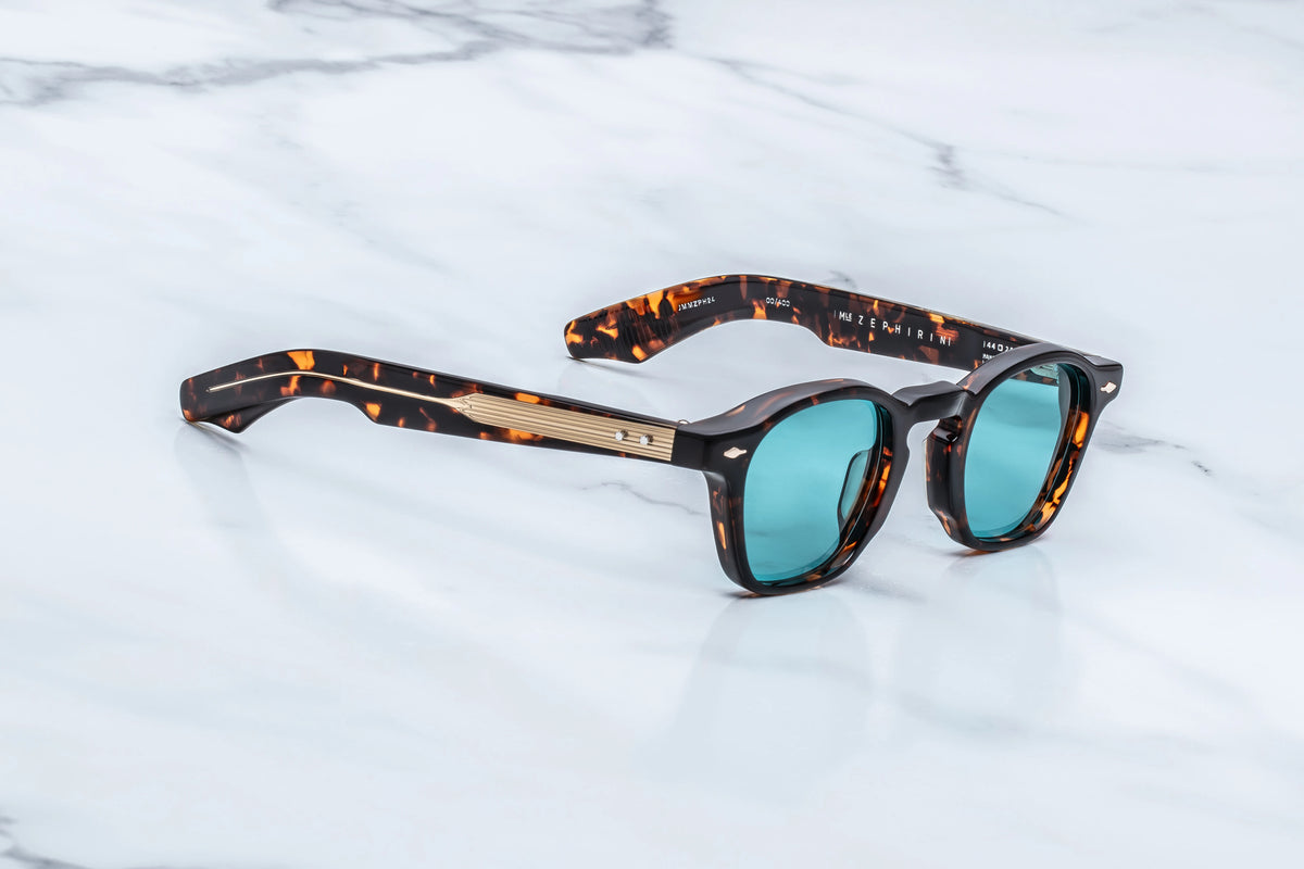 Jacques Marie Mage Zephirin tortoiseshell-patterned acetate spectacles with light blue lenses, featuring sculpted temple construction and gold metal hardware.