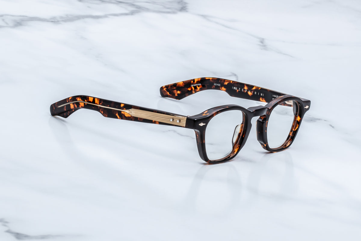 Tortoiseshell-patterned Jacques Marie Mage Zephirin spectacles with sculpted temple gold-tone metal details, resting on a white marble surface.