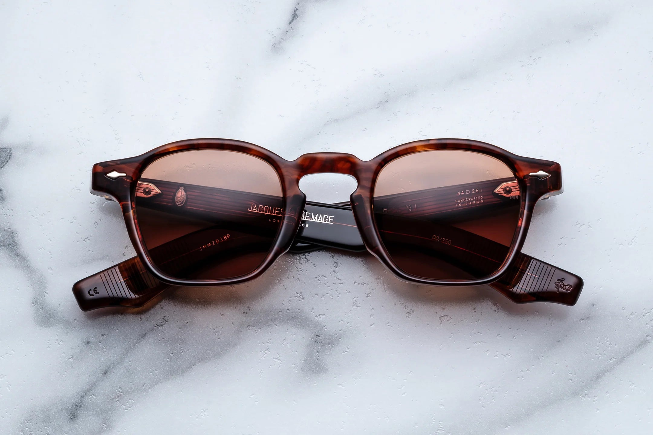 Brown tortoise acetate rectangular sunglasses with warm brown tinted lenses, photographed front-facing on a light marble surface.