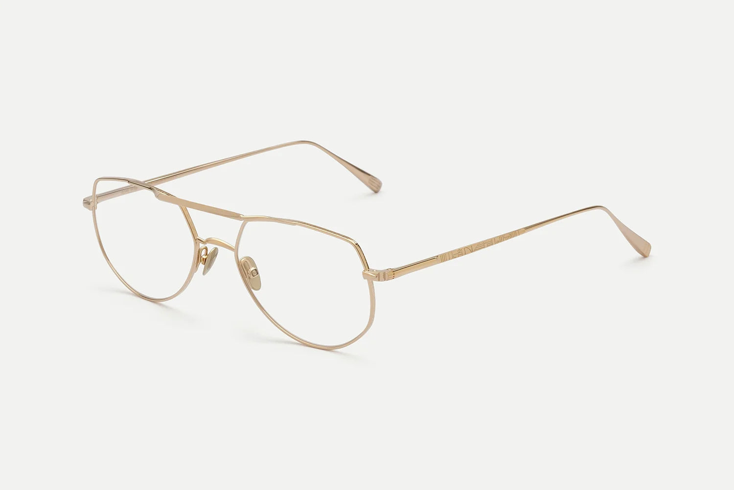 The AHLEM Cadet eyeglasses by AHLEM are handcrafted in France, featuring a gold metal aviator-style thin frame with clear lenses and adjustable nose pads, displayed on a white background.