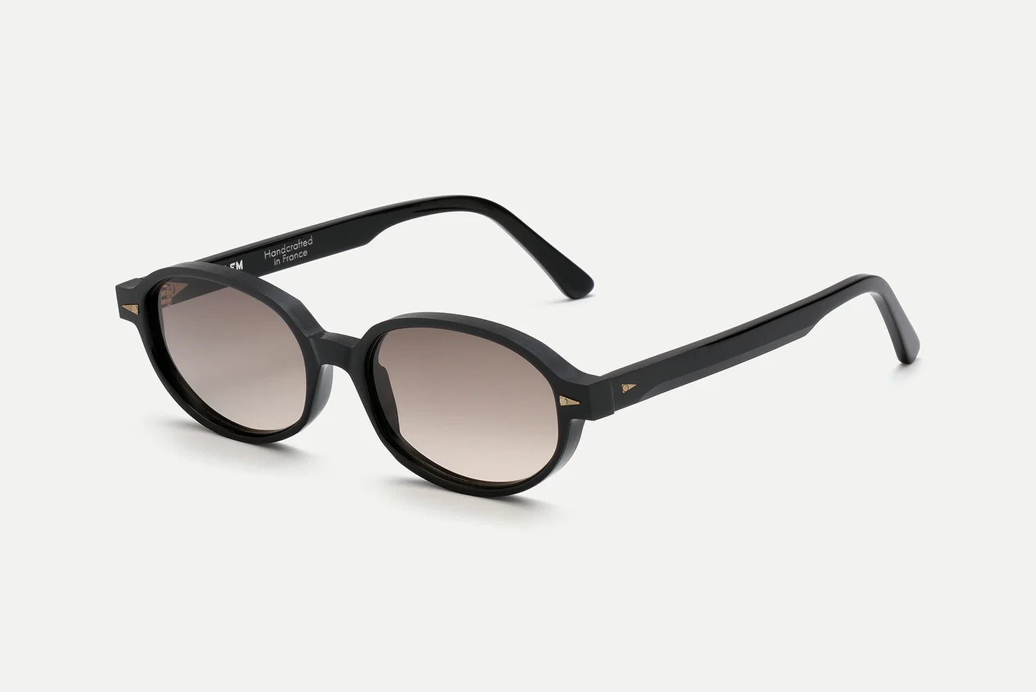 The AHLEM Rohan by AHLEM are black round sunglasses with dark gradient lenses, highlighted by gold accents on the temple corners and crafted from premium Italian acetate, displayed against a plain white background.