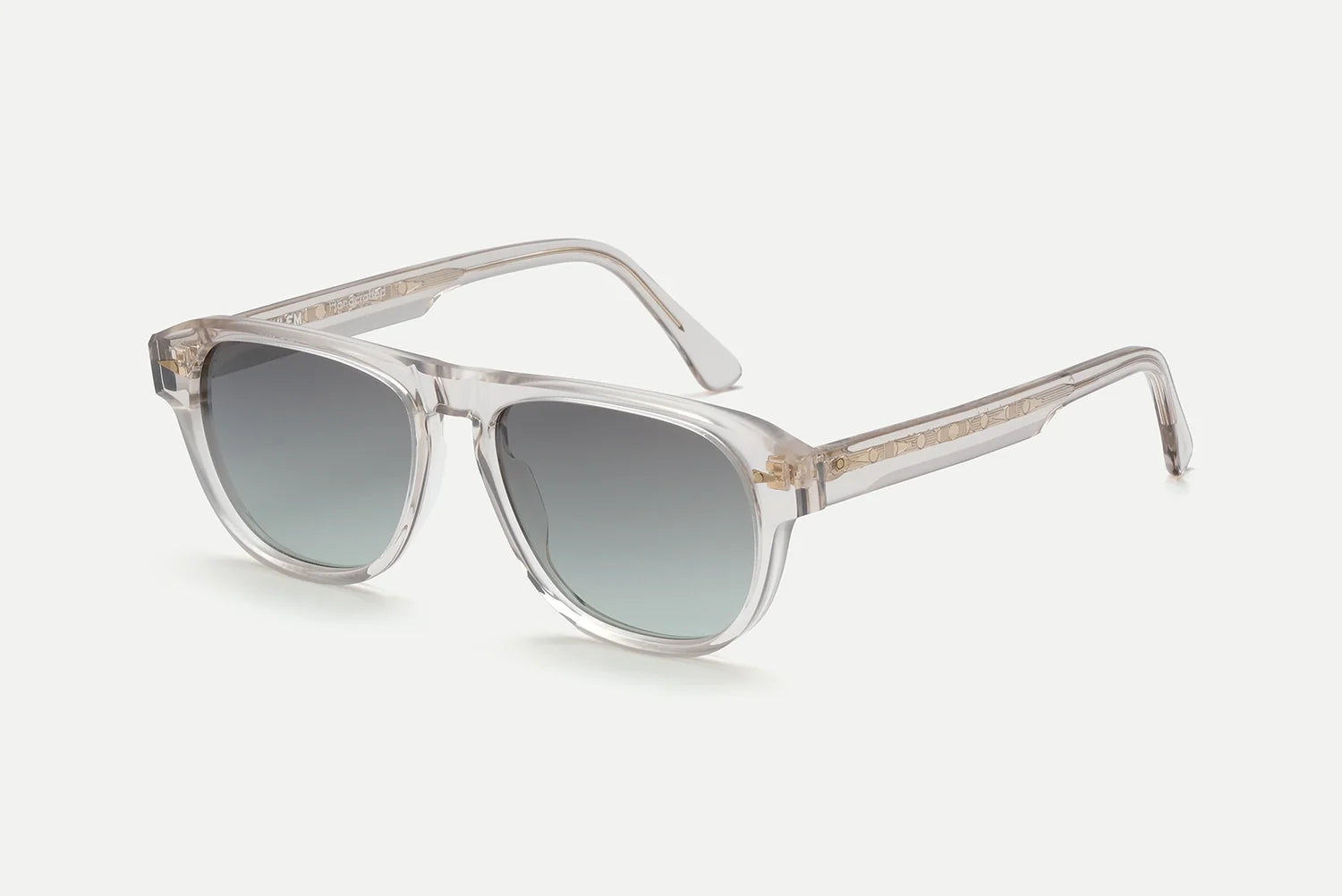 The AHLEM Carpentier sunglasses by AHLEM feature a clear acetate frame with square, softly rounded lenses that transition from dark gray at the top to lighter gray at the bottom. Expertly handcrafted in France from premium Italian acetate, these pilot-shaped sunglasses are finished with subtle gold detailing near the hinges on the arms. The background is plain white.