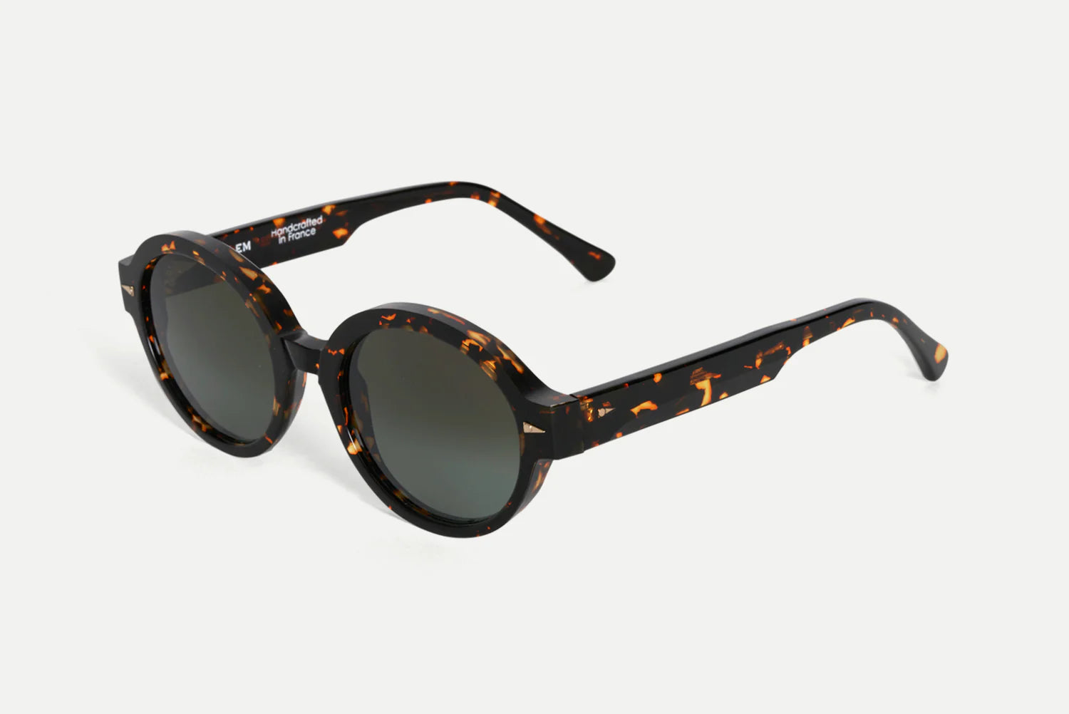Oval sunglasses with a dark brown and black tortoiseshell frame and dark gray lenses, shown on a light gray background.