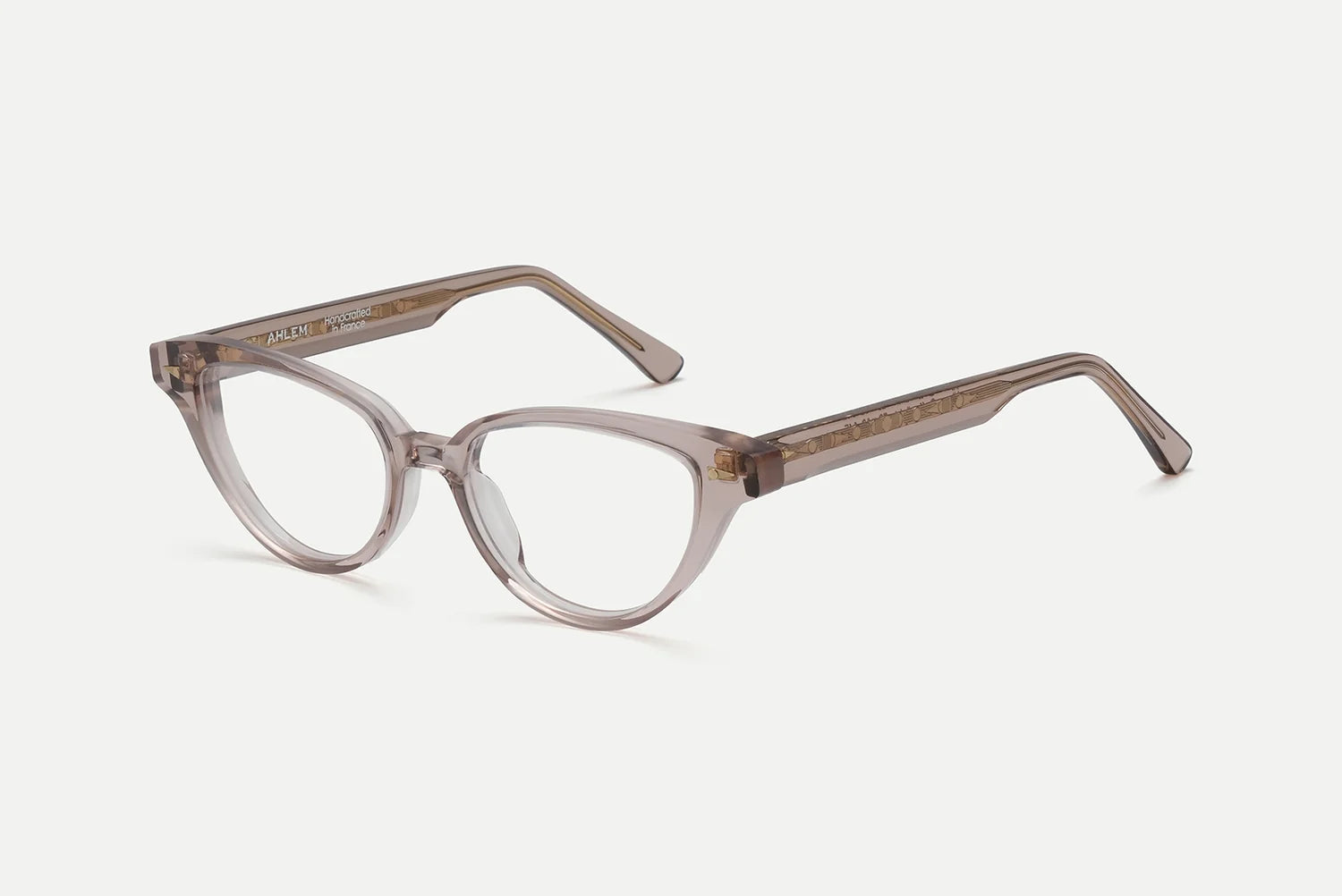 The AHLEM Lilas by AHLEM are clear, light brown cat-eye optical glasses featuring thick, angular frames and rounded lenses. Handcrafted in France from plant-based Italian acetate, they are displayed against a plain white background.