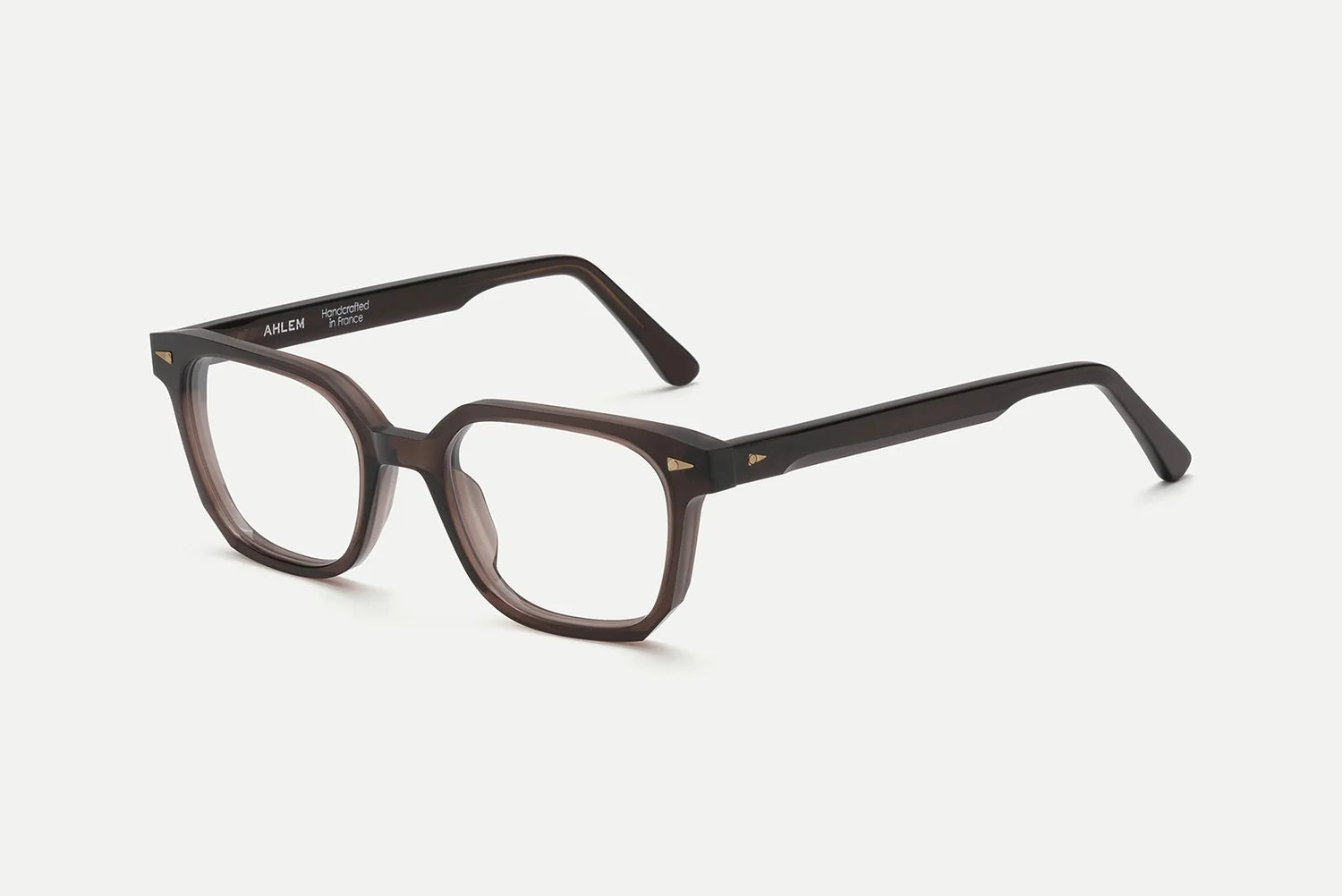 The AHLEM Houdon by AHLEM features brown rectangular eyeglasses with thick, handcrafted acetate frames and subtly rounded edges, displayed against a plain white background. The inside of the left arm is detailed with white text branding, while premium steel hardware lends an extra touch of sophistication to these distinctive square optical glasses.