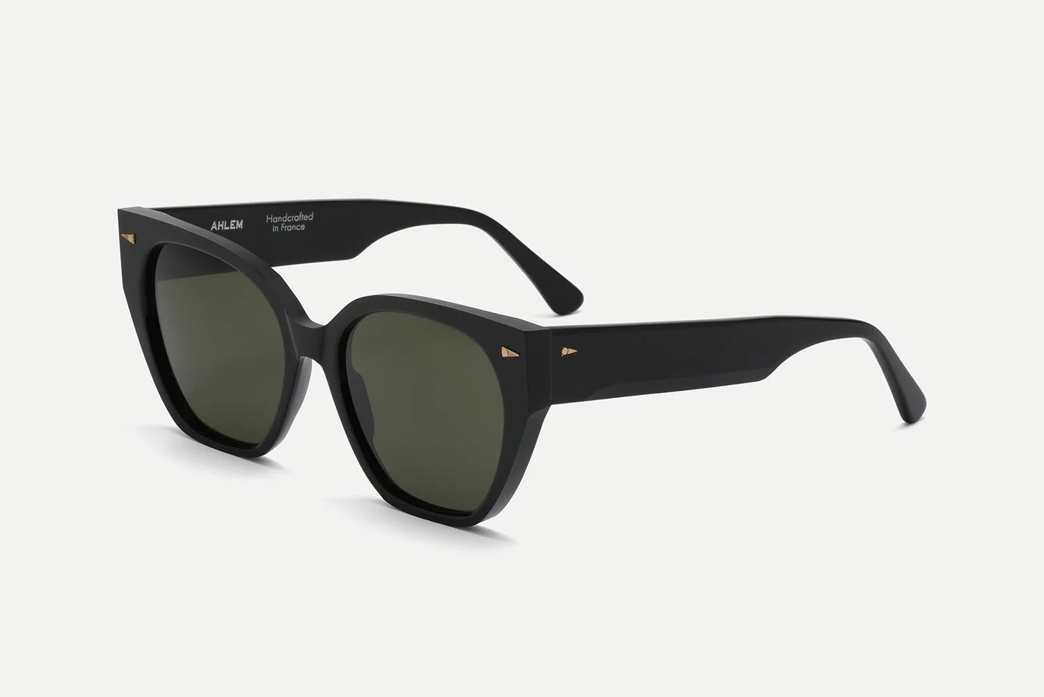 Black acetate sunglasses with olive green tinted lenses, thick sculptural temples, and small gold arrowhead accents, shown at an angled side view on a white background.