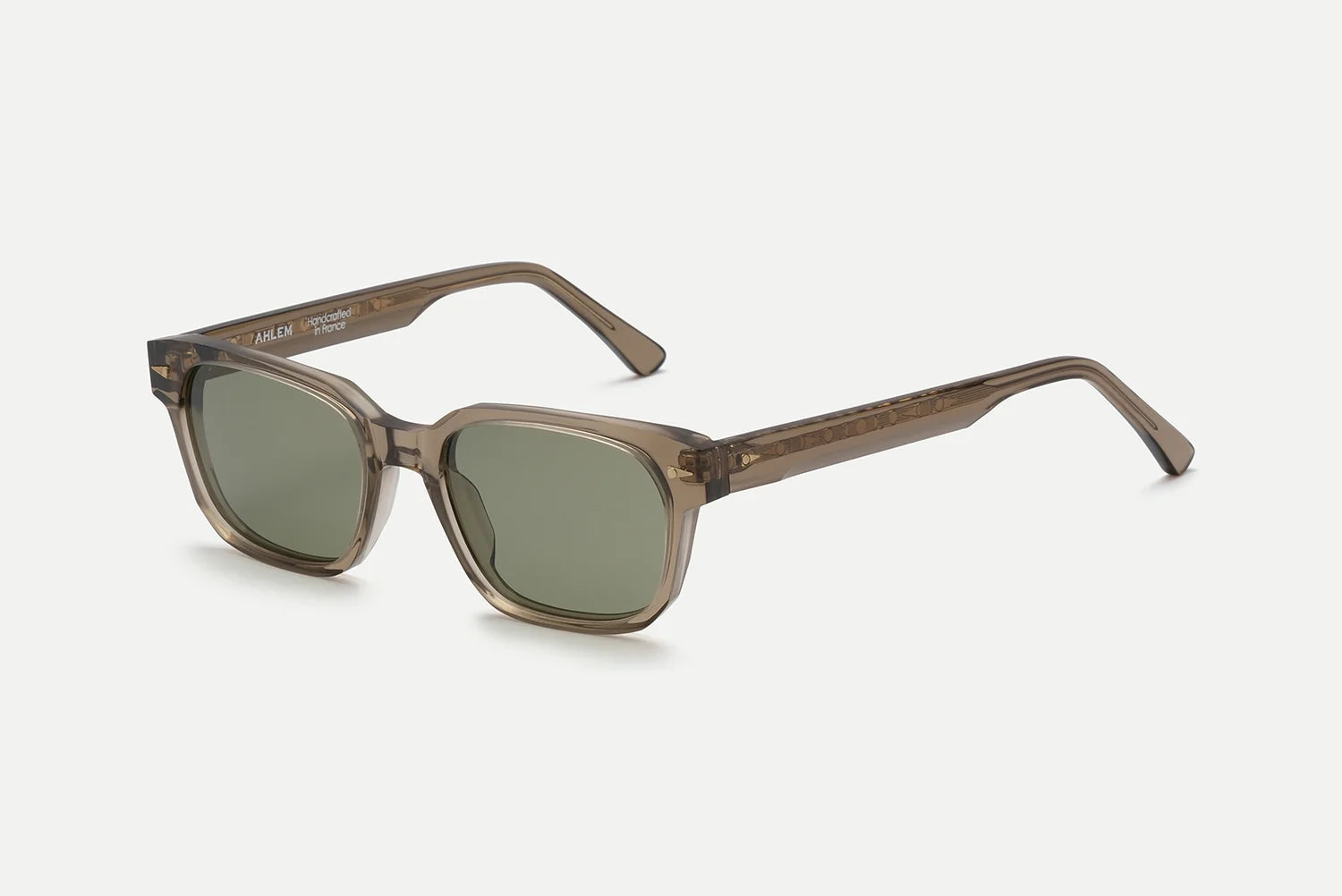 The AHLEM Sedaine sunglasses by AHLEM feature square frames crafted from translucent brown acetate and green-tinted lenses, expertly handcrafted to reflect refined French luxury. Presented against a plain light grey background, the AHLEM Sedaine highlights timeless style and meticulous craftsmanship.