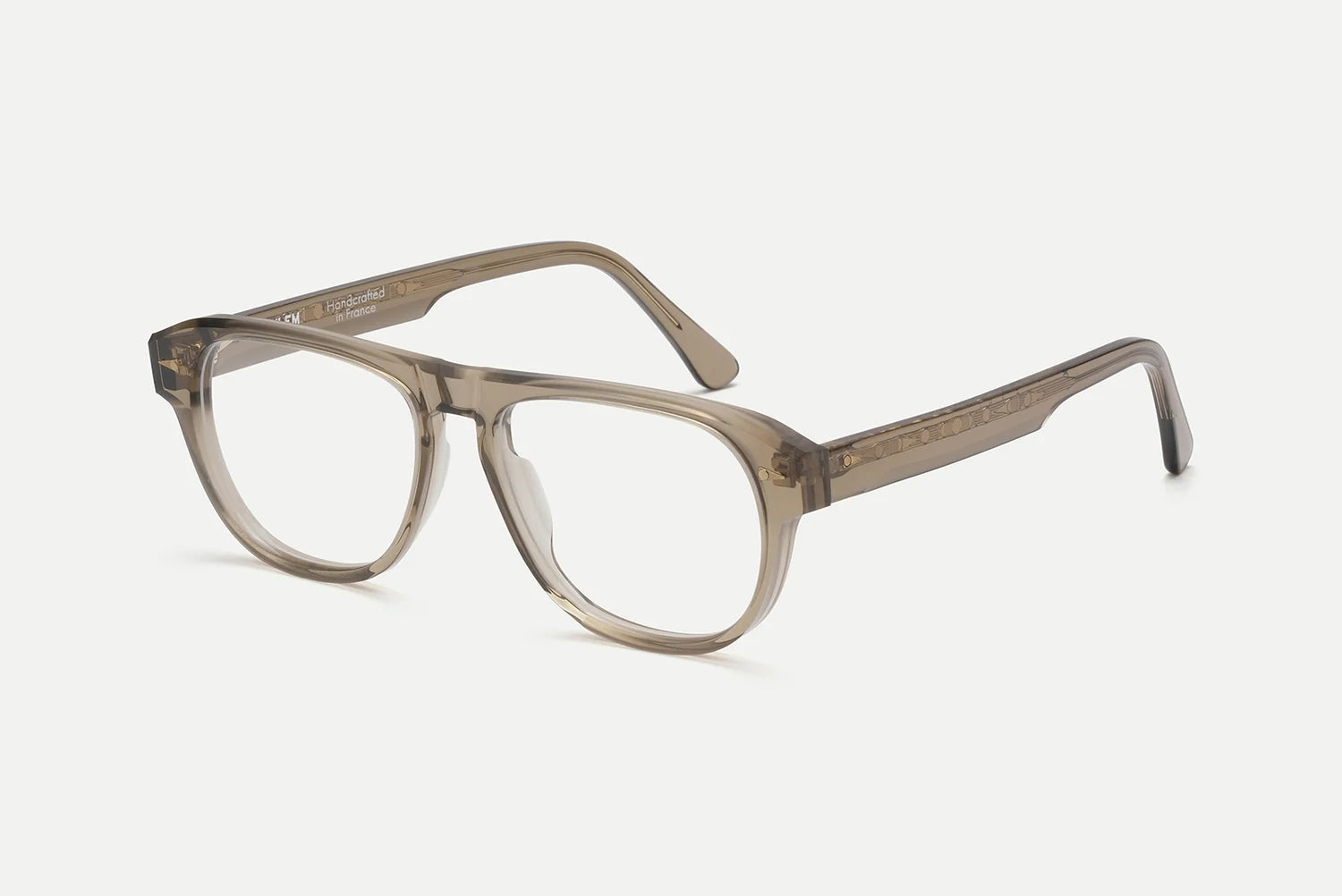 A pair of translucent acetate eyeglass frames in a smoky taupe-brown color, shown from a three-quarters angle on a light gray background.