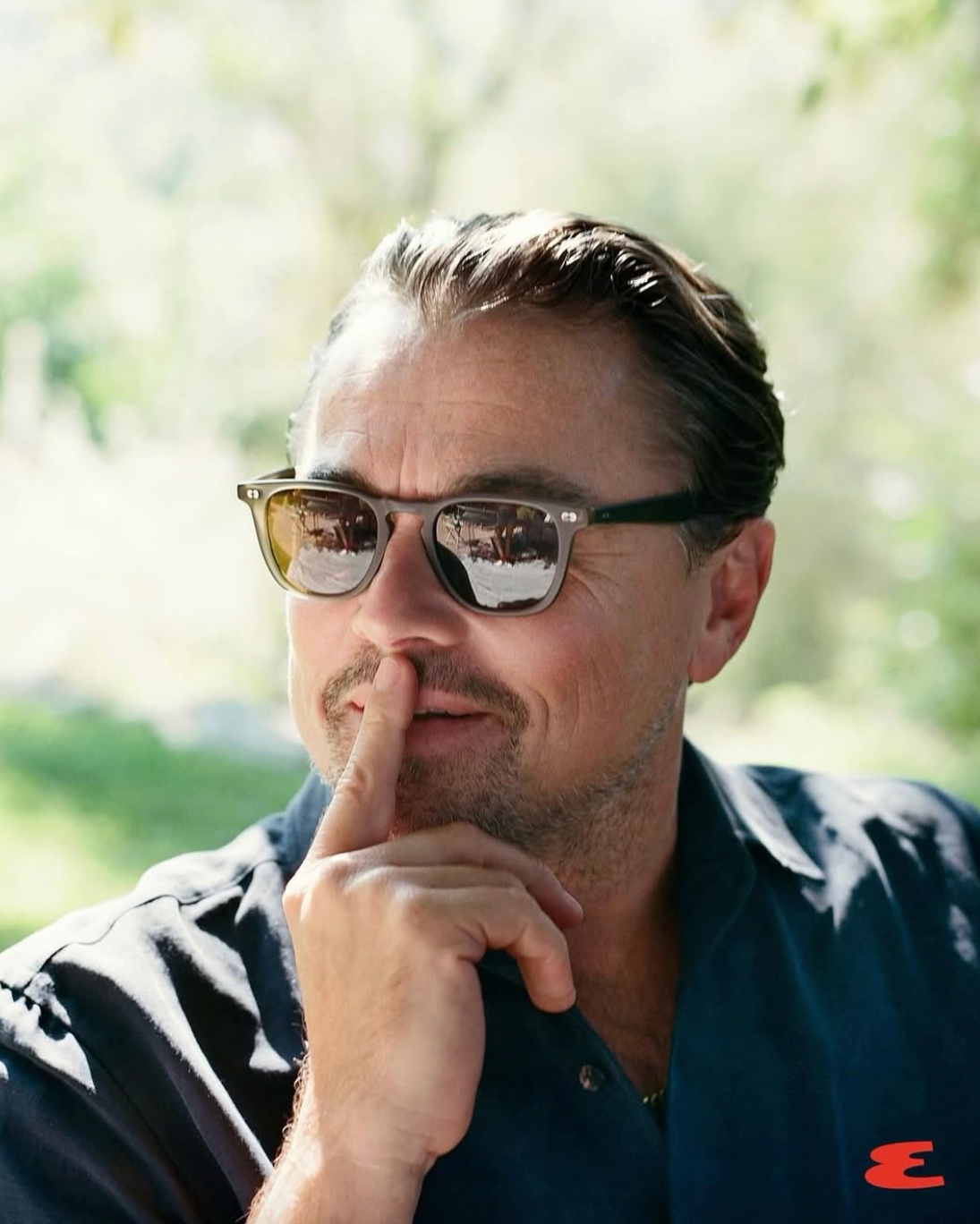 leonardo dicaprio wearing sunglasses with a blurred natural background
